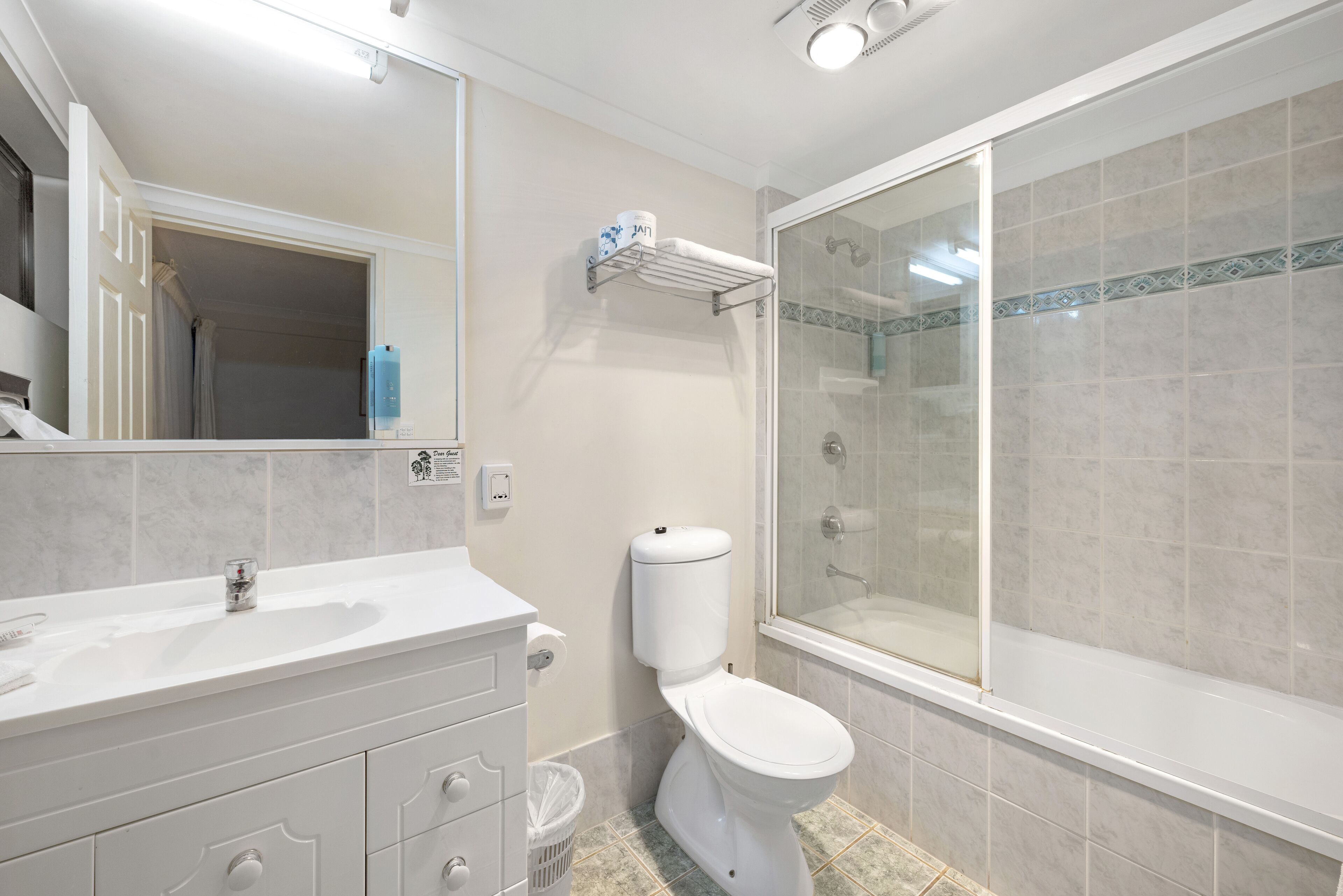 A bathroom with a white sink, vanity, toilet, and a glass-enclosed shower area.