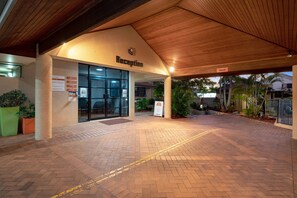 A reception area with a wooden ceiling, a glass entrance, and a brick floor. - Pegasus Motor Inn and Serviced Apartments (Hamilton)
