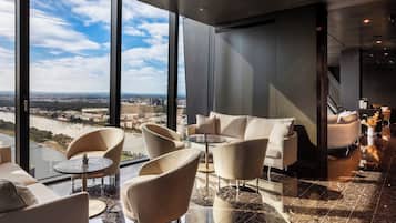 A modern hotel lobby with a panoramic city view, comfortable seating, and a spacious layout.