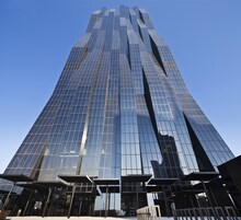 A tall, modern skyscraper with reflective glass windows and a prominent entrance area.