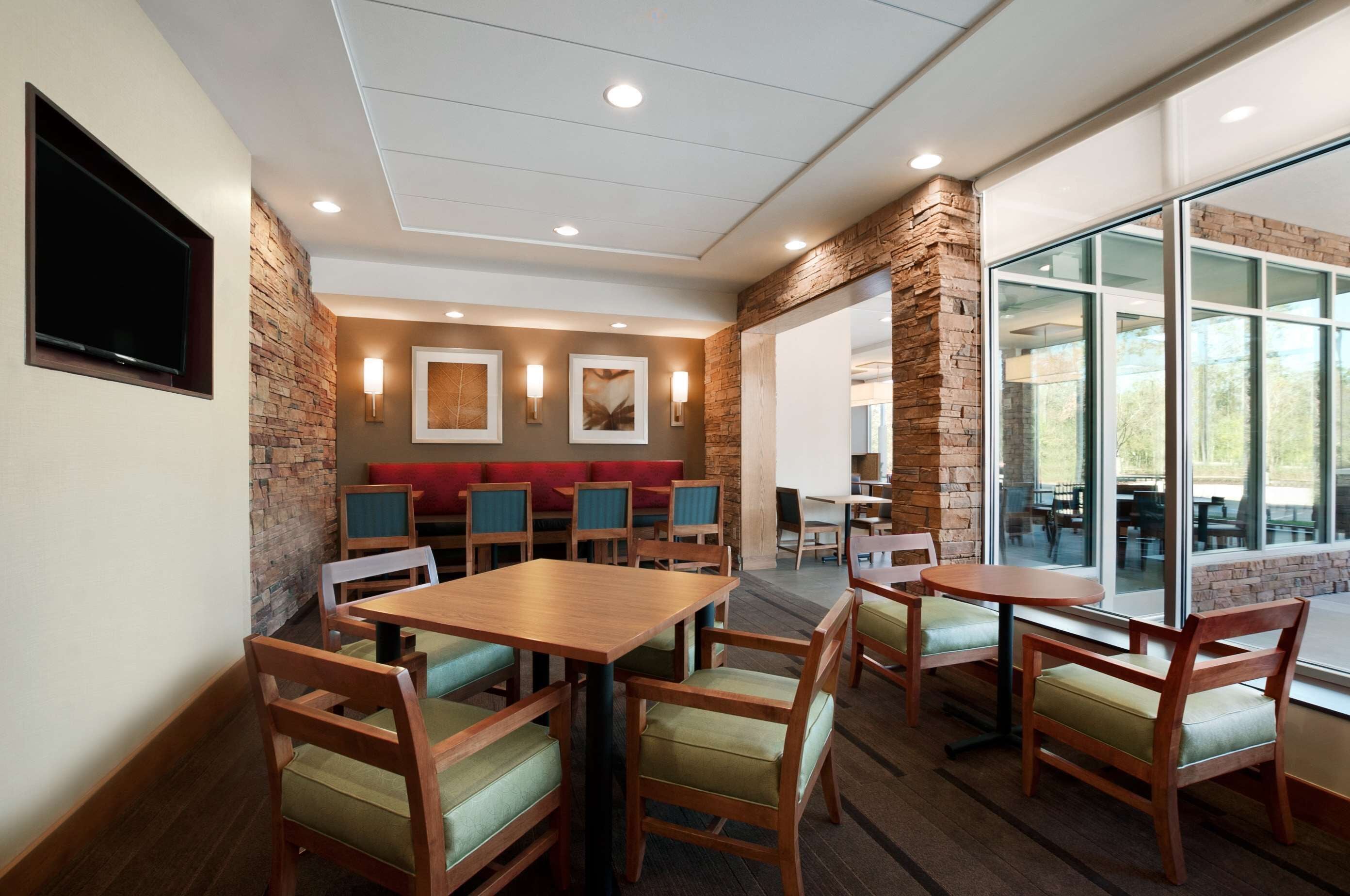 Un restaurante con mesas y sillas de madera, una pared de acento de piedra y un amplio ventanal con vistas.