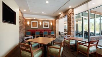 Un restaurante con mesas y sillas de madera, una pared de acento de piedra y un amplio ventanal con vistas.