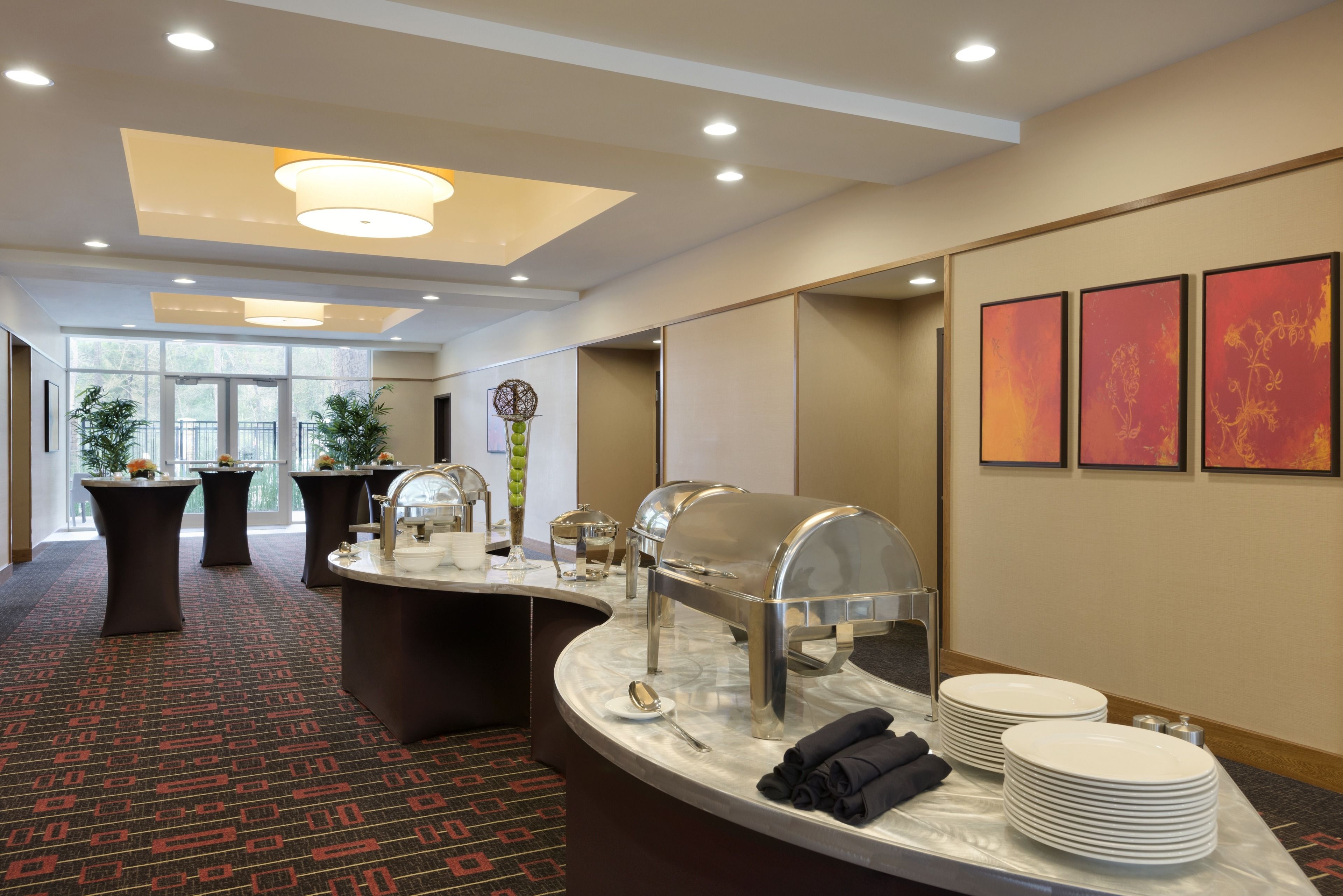 A hotel reception area with a buffet setup, including a food display, plates, and a water dispenser.