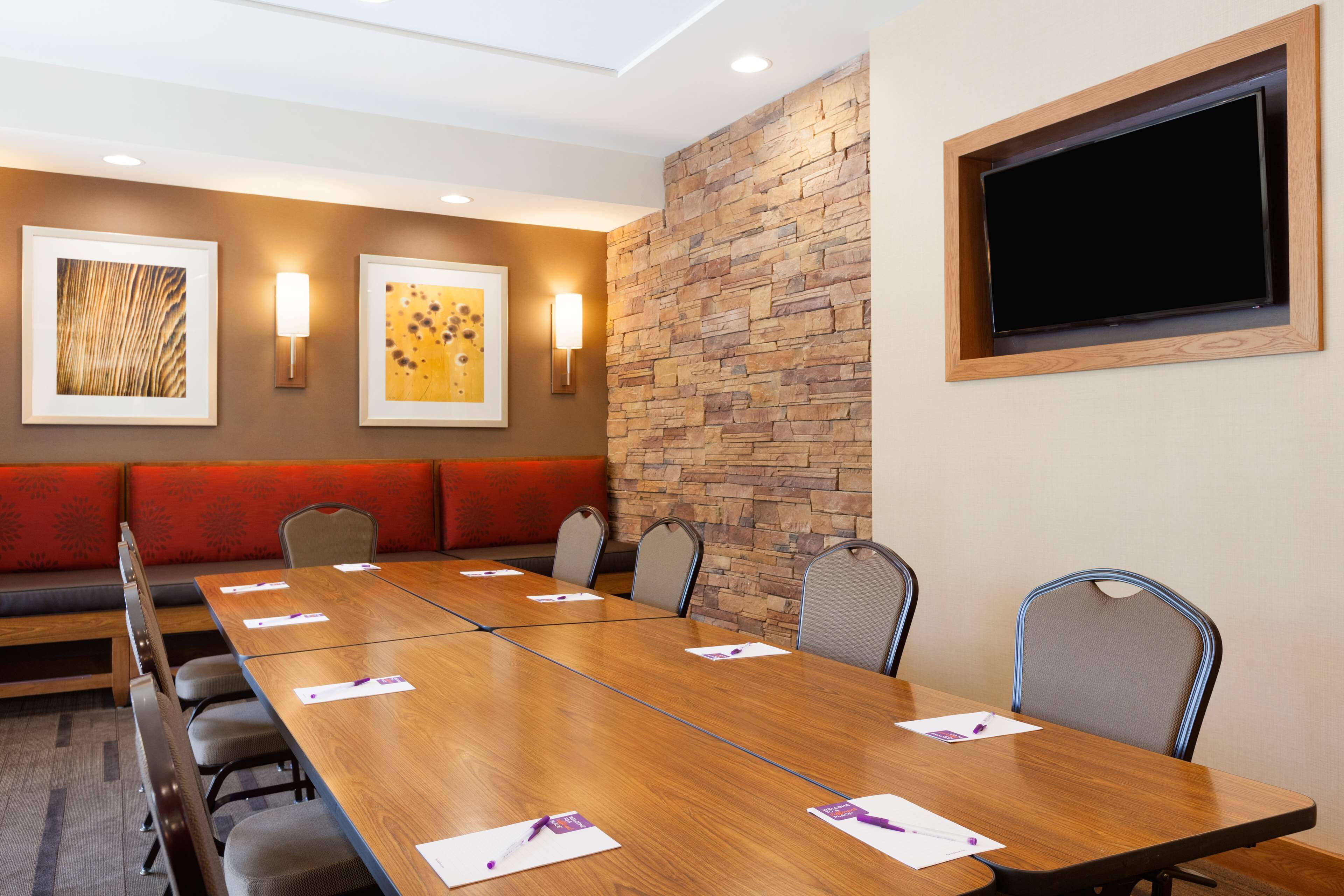 A conference room with a long table, chairs, a red sofa, and two framed artworks on the wall.