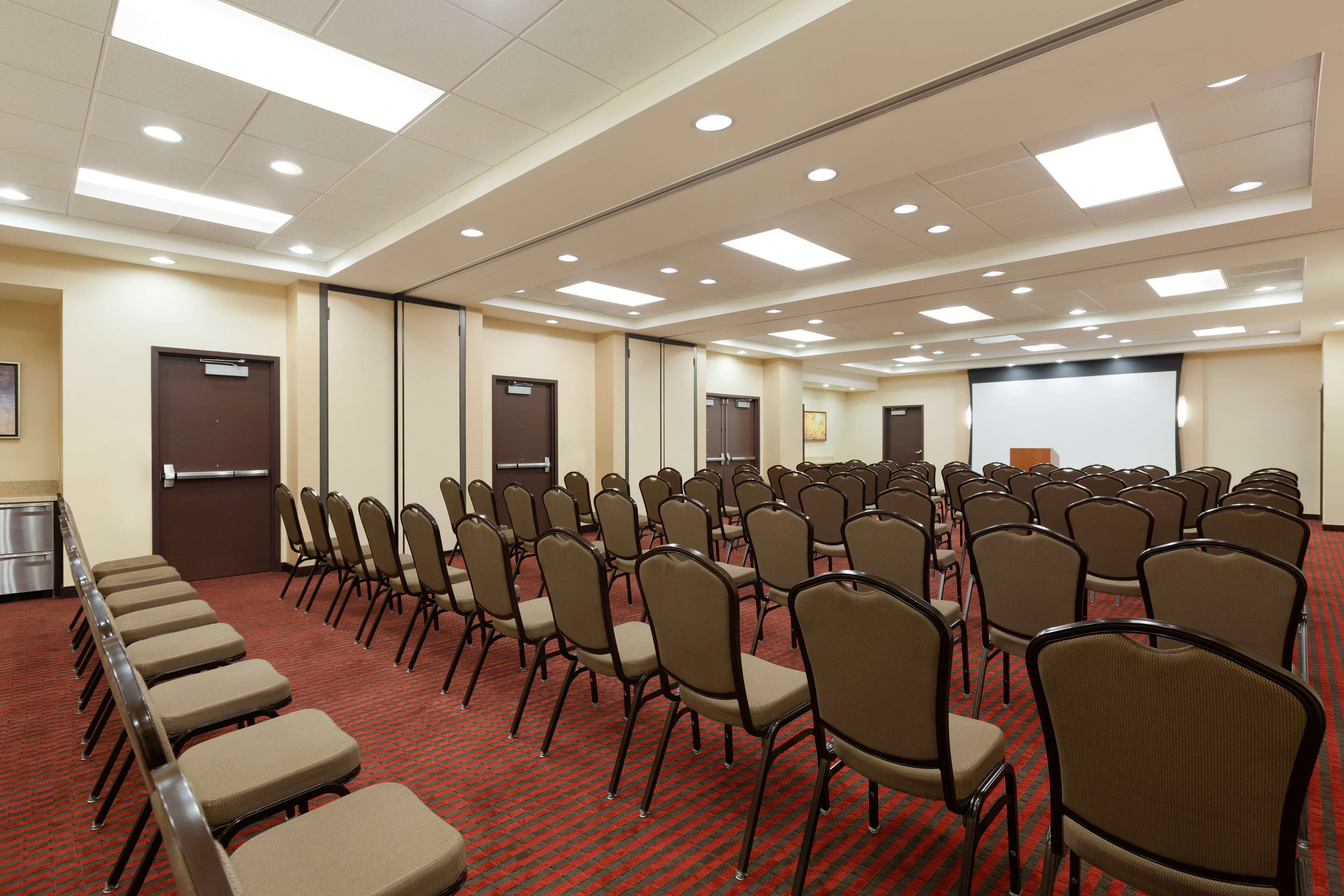 A conference room with rows of chairs and a projector screen.