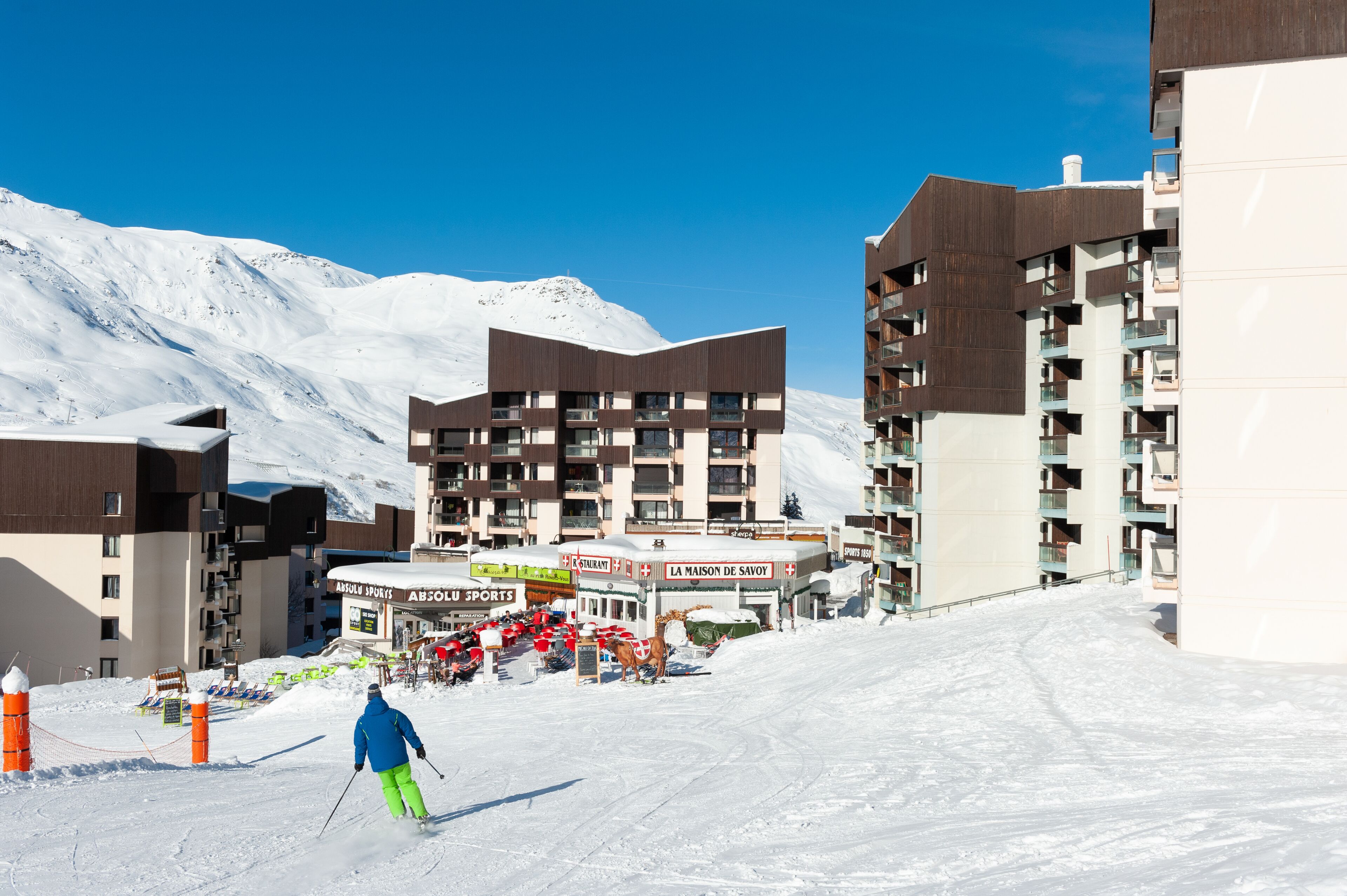 A ski resort with modern buildings, ski slopes, and a clear blue sky.