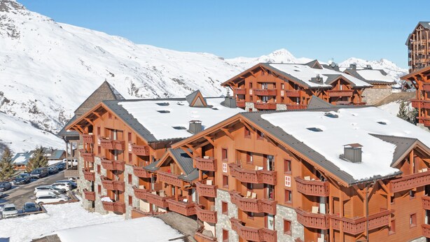 A large wooden lodge with multiple balconies and a ski slope in the background. - Résidence Pierre & Vacances Les Menuires Les Combes (Les Belleville)