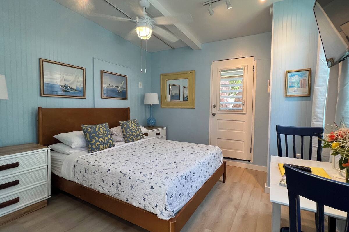 A bedroom with a bed, bedside tables, a desk, and a chair.