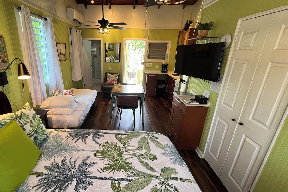 A room with a bed, a desk, a chair, a television, and a door.