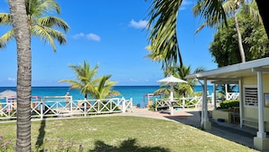 A beachside resort with a clear view of the ocean, a covered seating area, and a fenced patio. - Cottages by the Sea (Frederiksted)