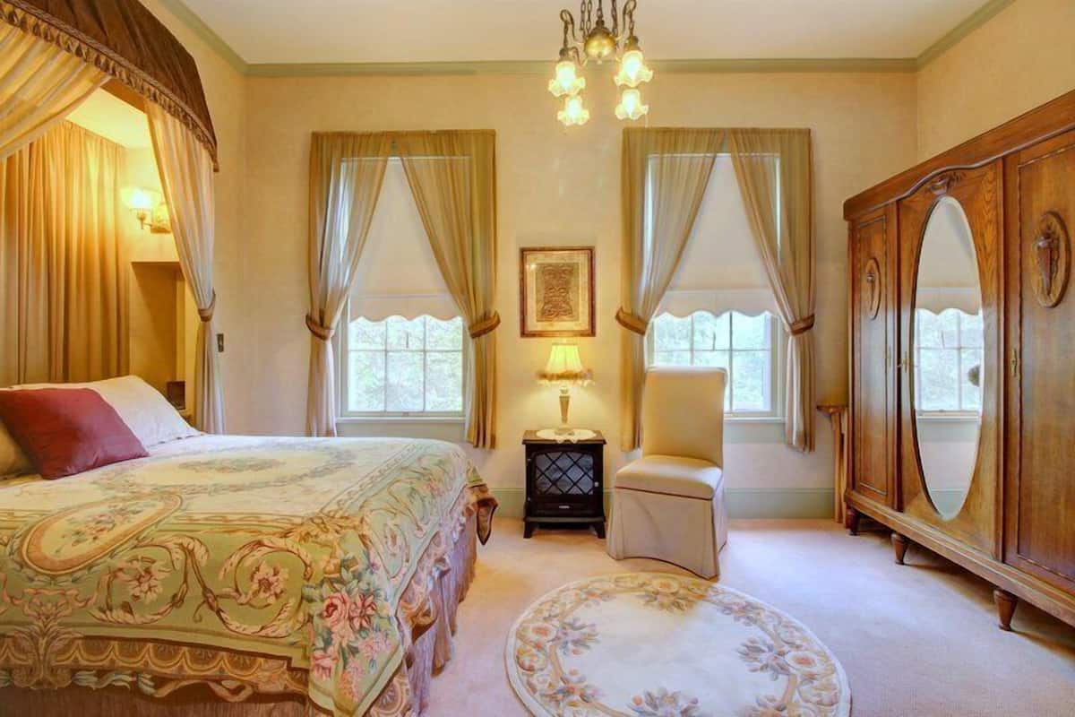 Quarto com uma cama grande, uma cadeira, uma cômoda e um abajur.