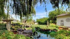 A serene garden with a pond, stone sculptures, and lush greenery. - Bybee's Historic Inn (Central Point)