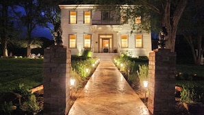 A two-story house with a front porch, a pathway leading to the entrance, and a statue on the right. - Bybee's Historic Inn (Central Point)