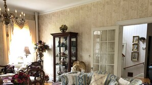 Ein traditionell eingerichtetes Wohnzimmer mit einem gemusterten Sofa, einem Glastisch und einer verzierten Engelsstatue.