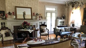 Ein traditionell eingerichtetes Wohnzimmer mit Kamin, einem blauen Sofa, einem Holztisch und einem gemusterten Teppich.