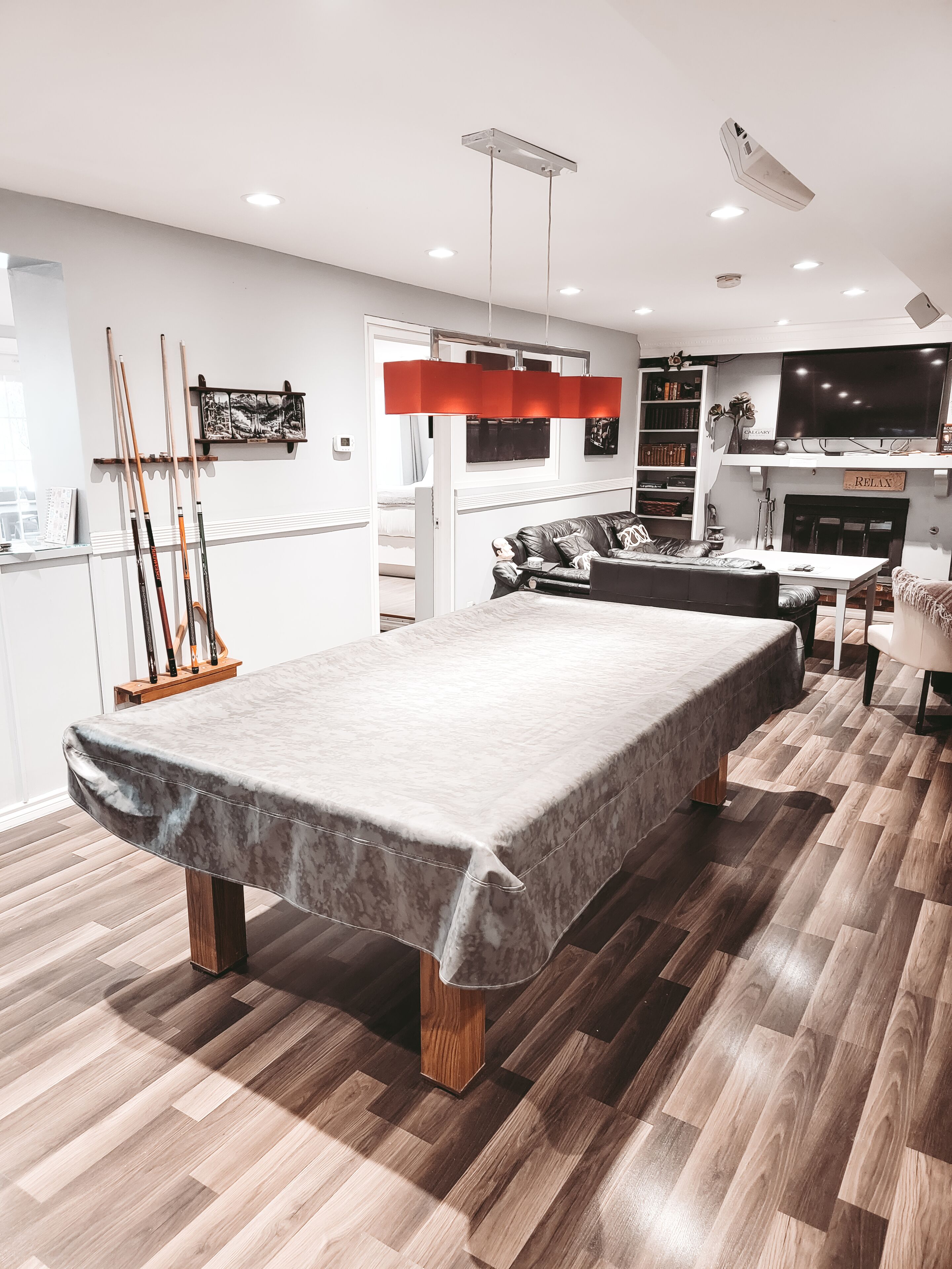 Un salon moderne avec une table de billard, un canapé, un téléviseur et une cheminée.
