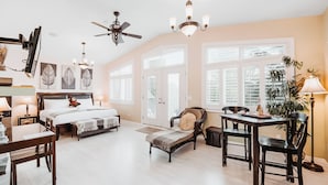 A spacious bedroom with a large bed, a desk, and a dining area. - Along River Ridge (Calgary)