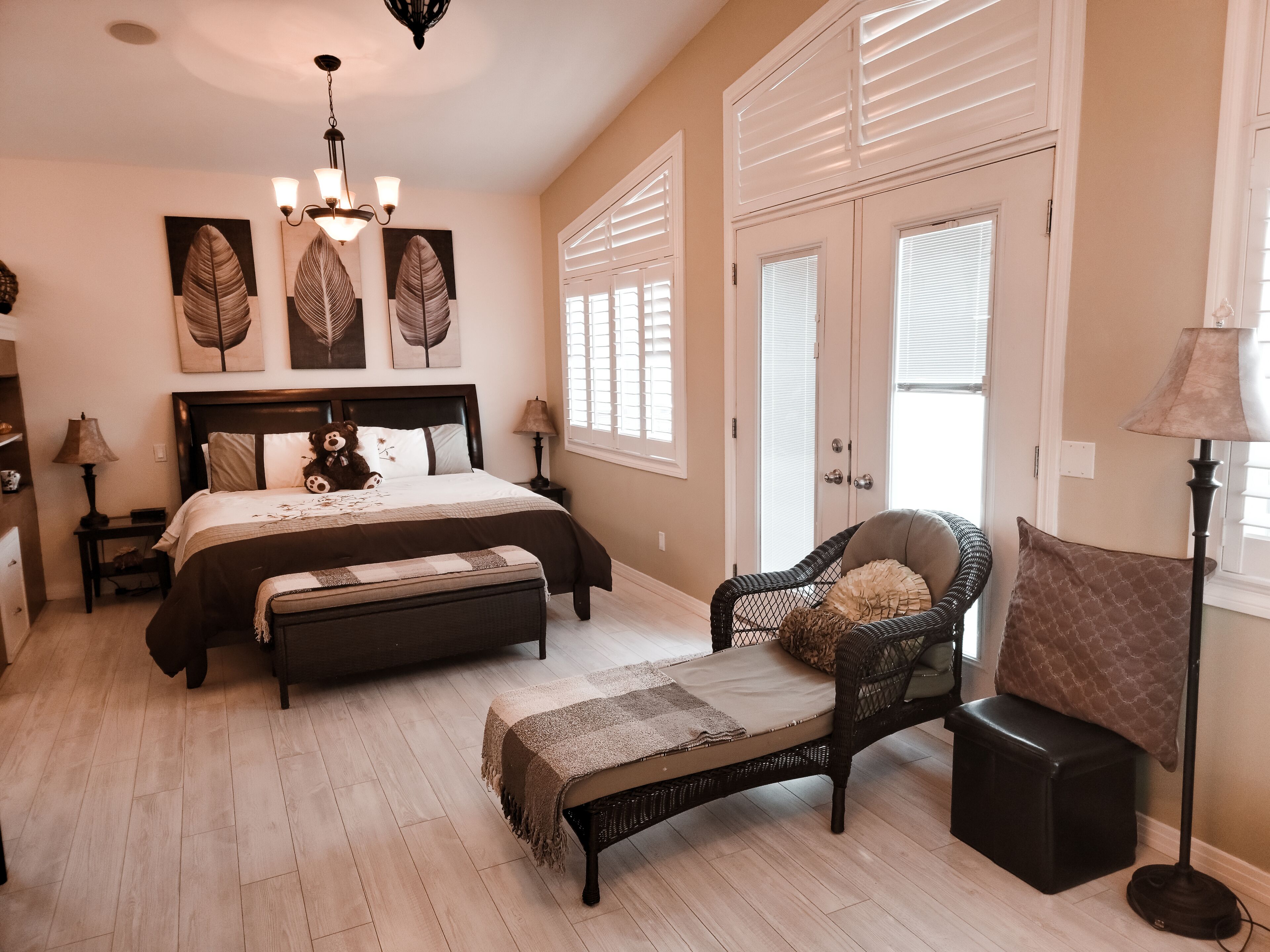 Une chambre à coucher avec un grand lit, une chaise, un banc, un bureau et une lampe.