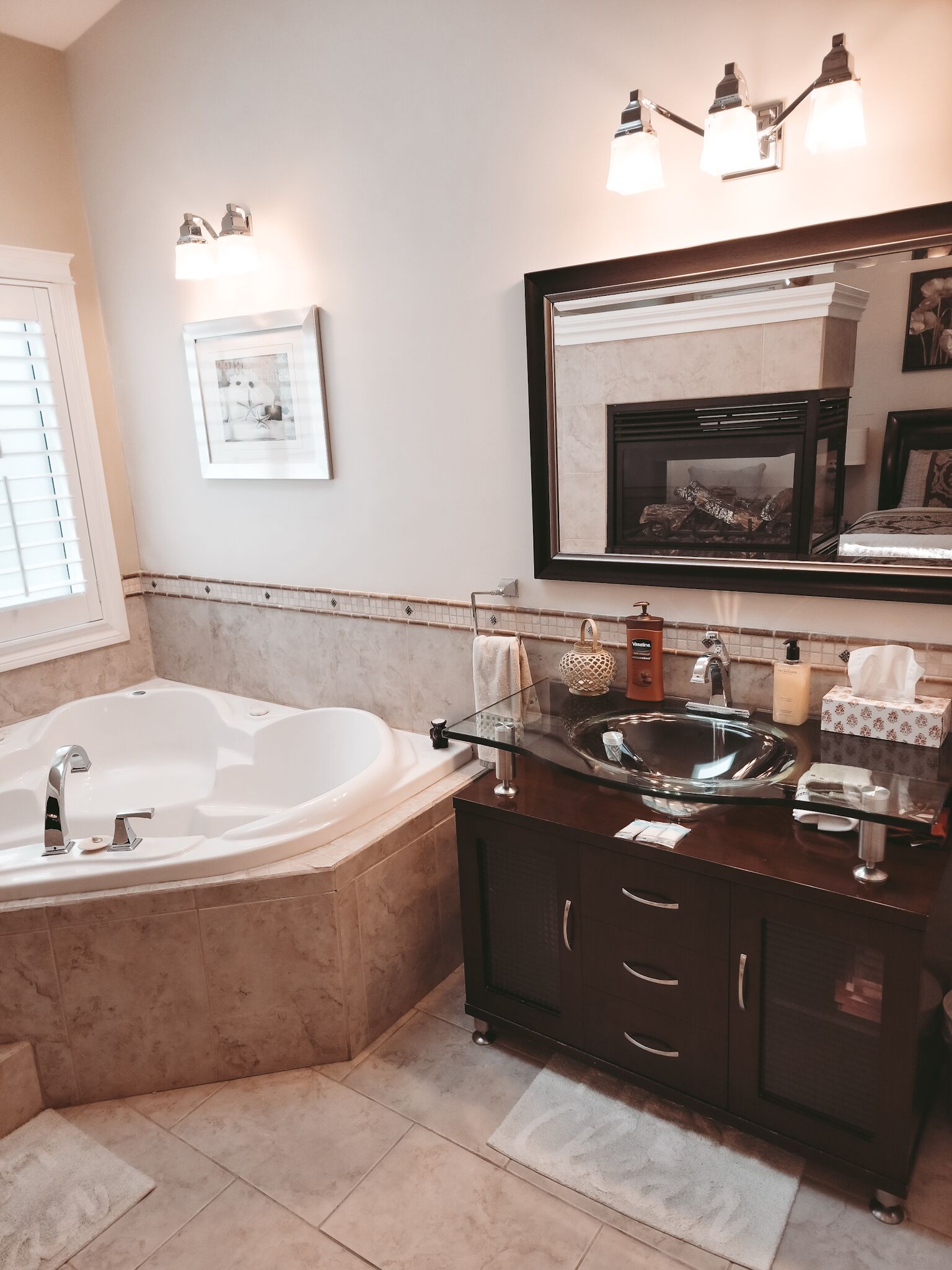 A modern bathroom with a freestanding bathtub, a vanity with a large mirror, and a wall-mounted light fixture.