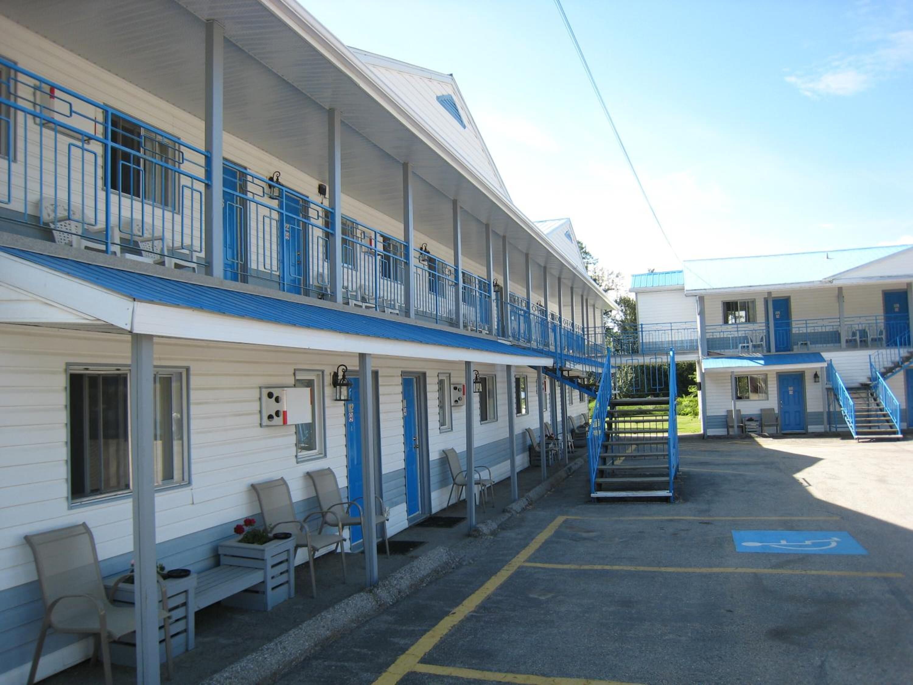A motel with two-story buildings, outdoor seating, and a parking area with handicapped accessibility.