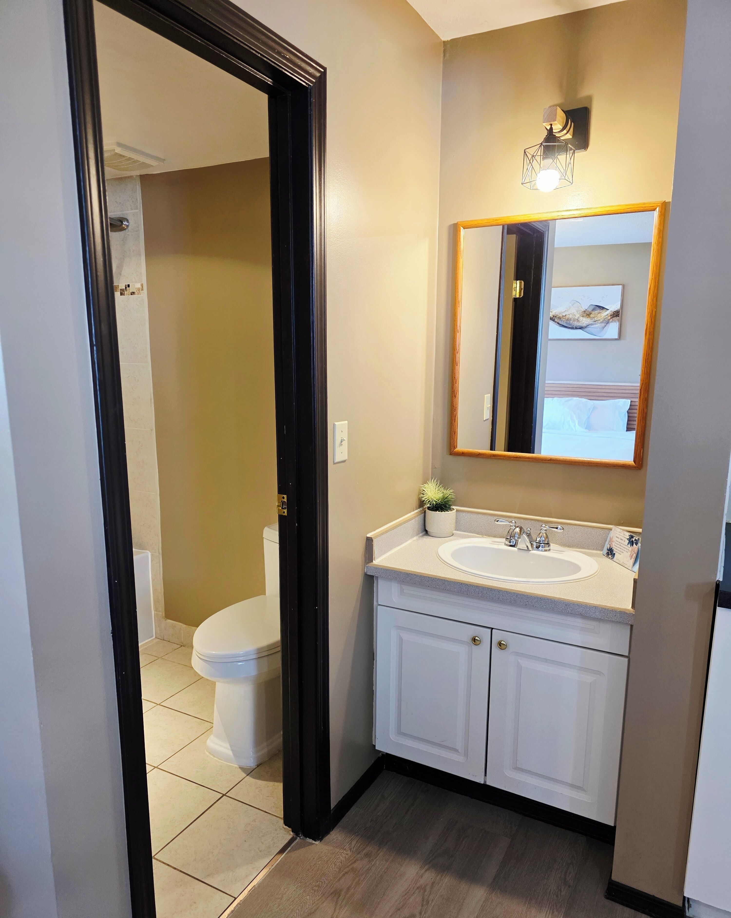A bathroom with a toilet, sink, and mirror.