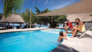A pool area with lounge chairs and a thatched-roof structure.