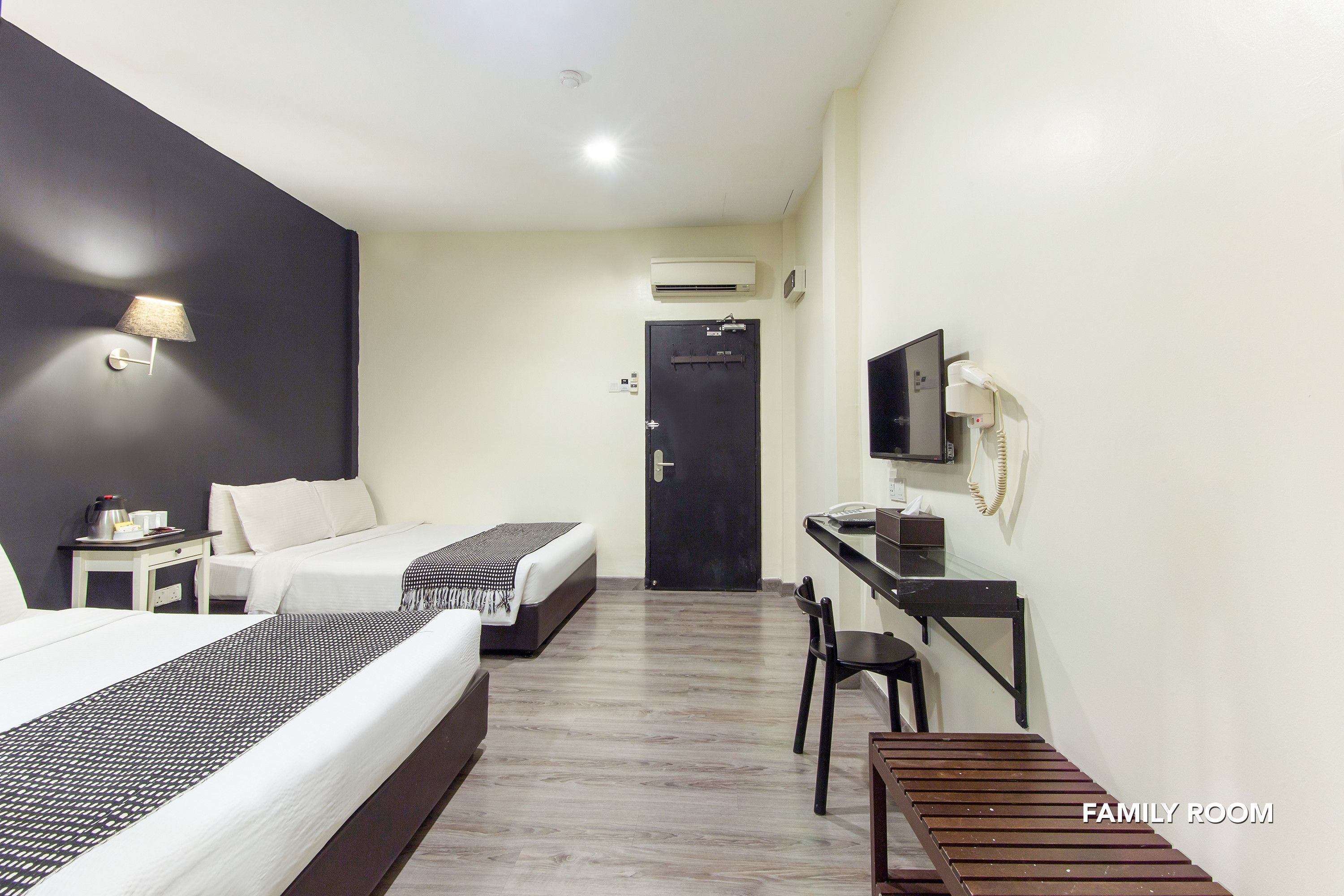 A family room with two beds, a desk, a chair, and a TV.