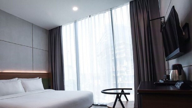 Een moderne hotelkamer met een groot bed, een klein rond tafeltje, een televisie en een koffiezetapparaat.