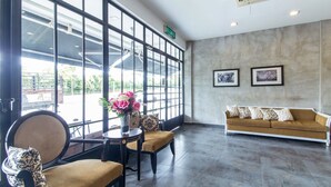 Een receptie met een bank, stoelen, een vaas met bloemen en een groot raam met uitzicht.