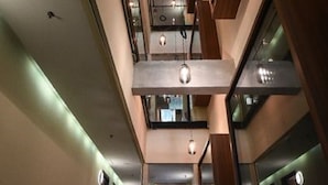 Een modern interieur met een centrale gang, aan weerszijden voorzien van balkons en grote ramen.