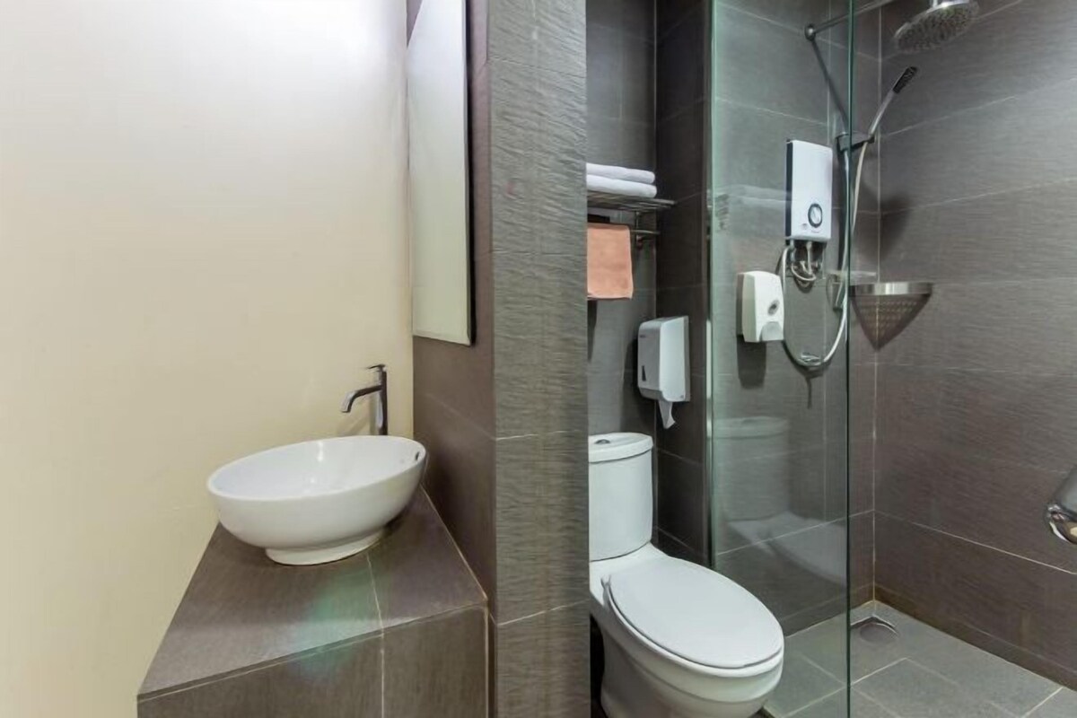 Een moderne badkamer met een wastafel op voet, toilet en douche met glazen wanden.