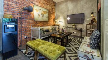 Una sala de estar moderna con una pared de ladrillo, un televisor de pantalla plana, un sofá, una mesa de centro y un reposapiés verde.
