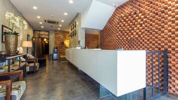 A reception area with a modern design, featuring a white reception desk, a brick wall with a unique honeycomb pattern, and a seating area with sofas and a coffee table.
