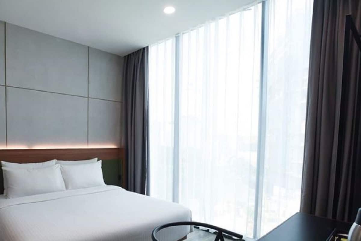 Una habitación de hotel con una cama grande, un escritorio y una ventana con cortinas.