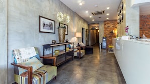 Een moderne lobby met een receptiebalie, een zithoek en een bakstenen muur.