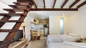 Une chambre avec deux lits, une télévision et un coin cuisine équipé d’un réfrigérateur et d’un four à micro-ondes.