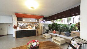 Un espace d’accueil moderne comprenant un comptoir de réception en bois, un canapé et une table basse agrémentée d’un arrangement floral.