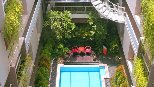 Une cour avec une piscine, un espace salon extérieur et une vue sur les bâtiments environnants.