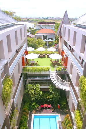 Ein Innenhof mit Pool, Sitzgelegenheiten im Freien und Blick auf umliegende Gebäude.