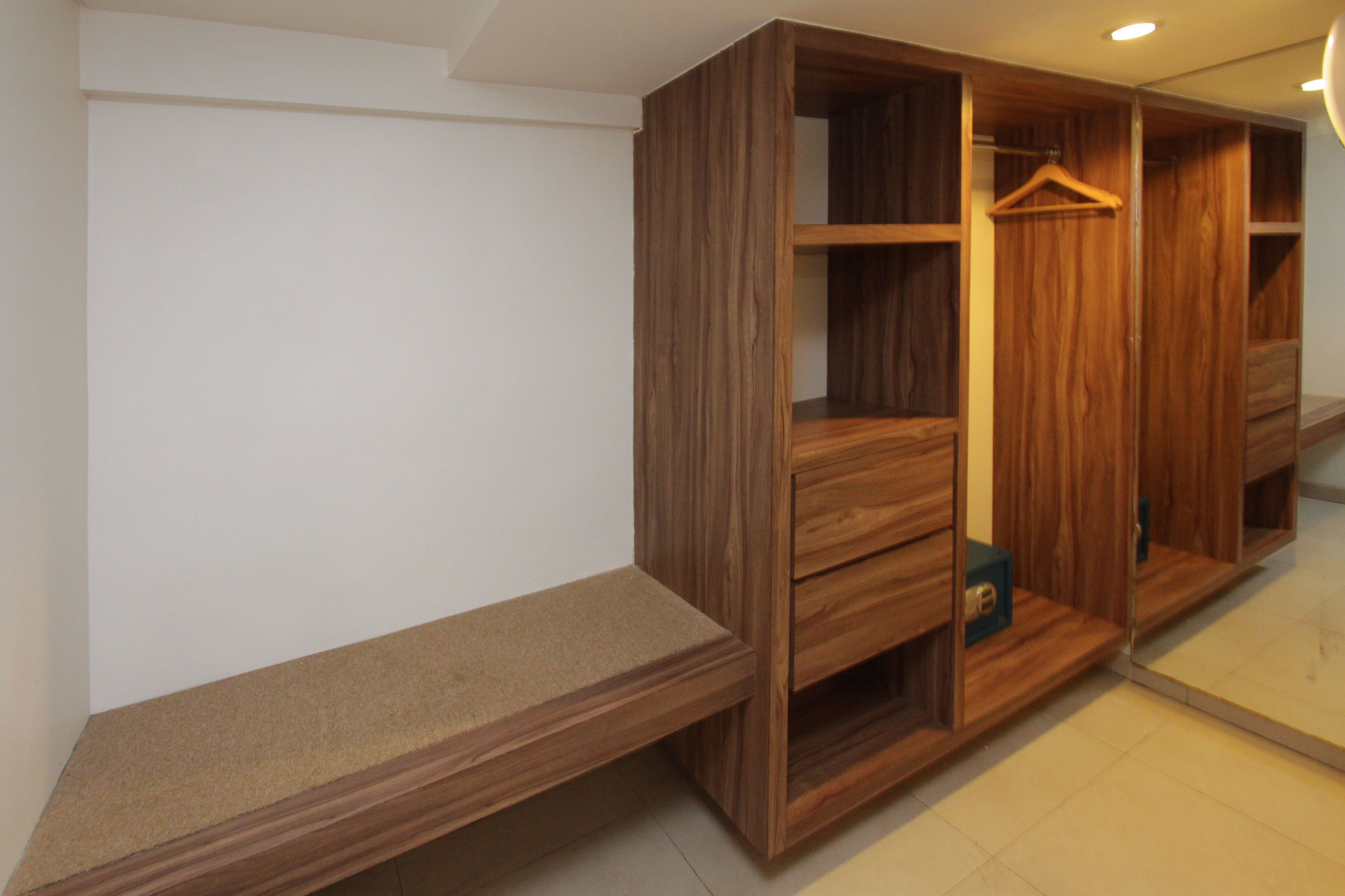 Un vestidor con estanterías y cajones de madera, un banco y una barra para colgar ropa.