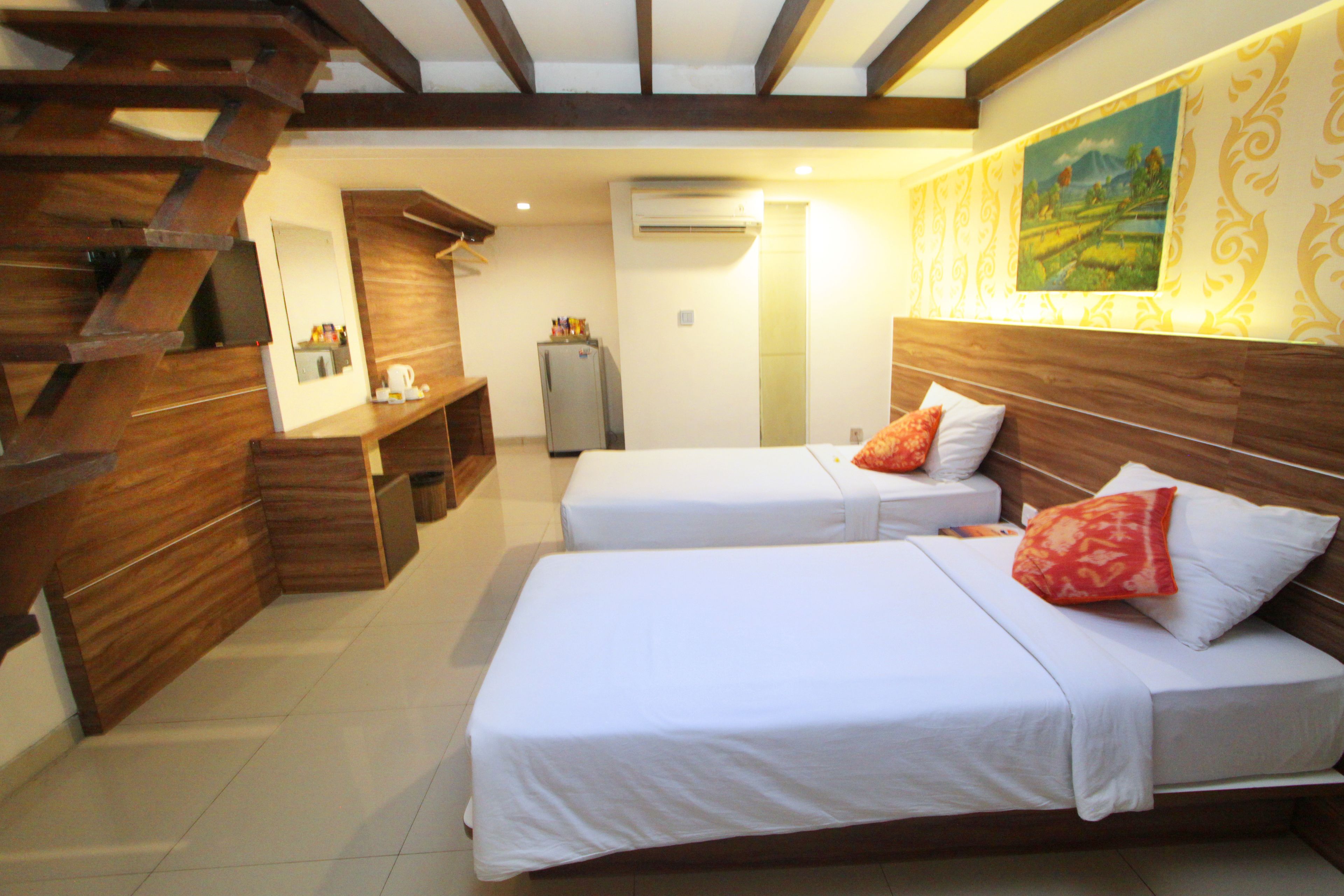 A hotel room with two beds, wooden furniture, a desk, and a painting on the wall.