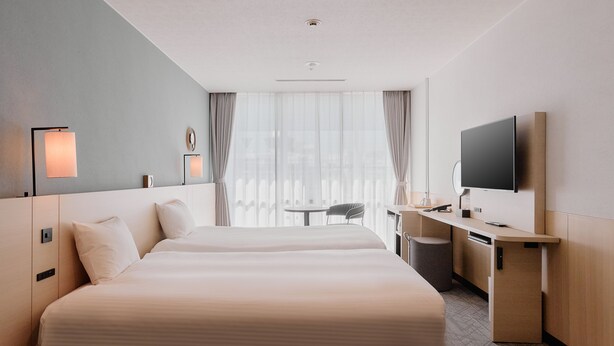 A hotel room with two beds, a desk, a chair, a TV, and a window with curtains. - Kyoto Tower Hotel (Kyoto)