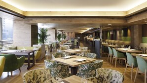 A modern restaurant with wooden tables and green upholstered chairs, featuring a central walkway and a view of the city. - Kyoto Tower Hotel (Kyoto)