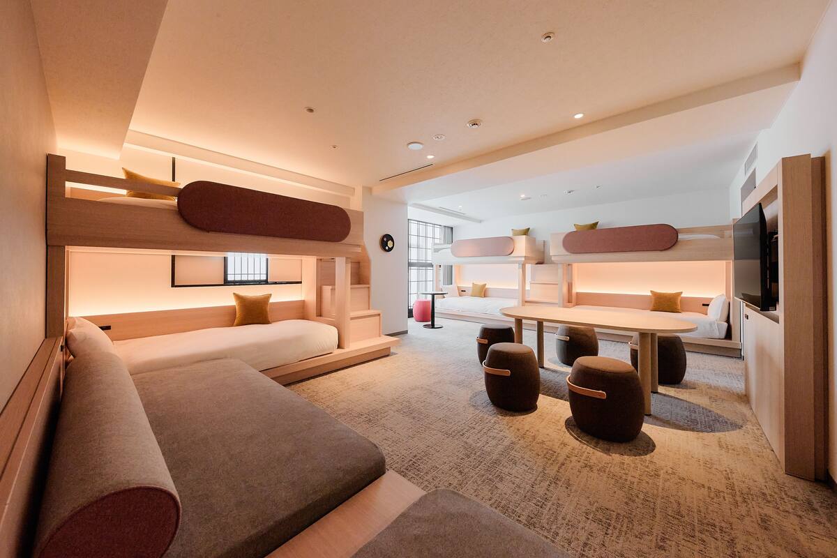 A modern hotel room with a cozy seating area, a dining table, and a flat-screen TV.