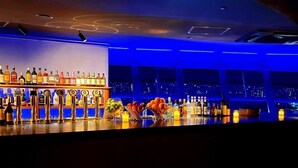 A bar with a variety of liquor bottles and a city view through large windows. - Kyoto Tower Hotel (Kyoto)