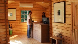 Interior de una cabaña de madera con un escritorio, una computadora y cuadros en las paredes.