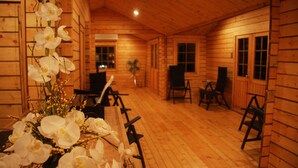 Interior de una cabaña de madera con comedor, sillas y una mesa.