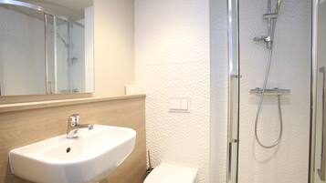 Ein modernes Badezimmer mit Waschbecken, Toilette und einer Duschkabine aus Glas.