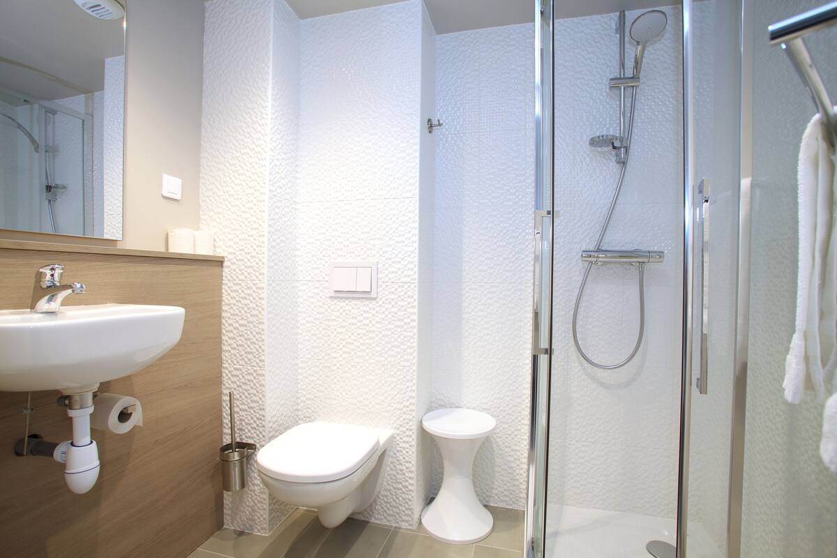 Une salle de bain moderne équipée d’un lavabo, de toilettes, d’un bidet et d’une douche à parois de verre.