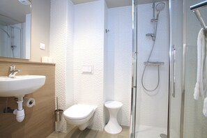 Un baño moderno con lavamanos, inodoro, bidé y ducha con mampara de vidrio.